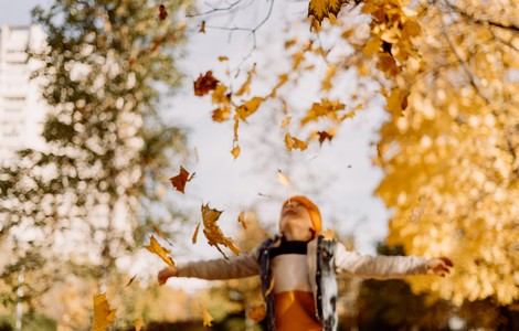 Ett barn som kastar upp löv i luften.
